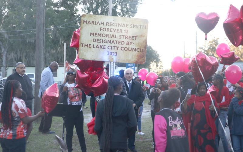 Todneisha Filer, the mother of Mariah Reginae Smith, stands amid red balloons next to the sign dedicated to her daughter’s memory Monday after she was shot and killed in August. (MORGAN MCMULLEN/Lake City Reporter)