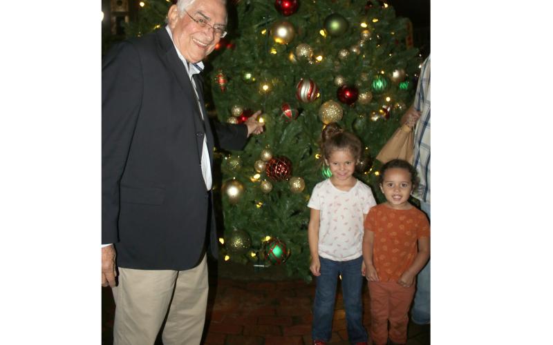 Lake City Mayor Stephen Witt (from left) stands with Aleah Hillhouse, 5, and Autumn Hillhouse while showing the youngsters ornaments on the city’s Christmas Tree during Sunday’s tree lighting ceremony. (TONY BRITT/Lake City Reporter)