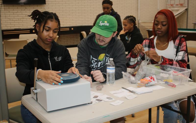 Zamaria Granado (from left) and Hunter Neeley work on making dog tag necklaces for Florida Gateway College students on Wednesday morning. The necklace-making sessions and other activities were part of the school’s welcome back activities for the spring semester. (TONY BRITT/Lake City Reporter)