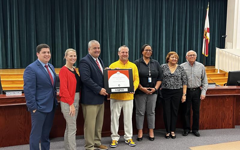 Columbia High Principal Trey Hosford (middle) is presented a framed certificate in honor of the school having 100 years of continuous accreditation. Joining Hosford are School Board members Hunter Peeler (from left) Dana Brady-Giddens, Superintendent Lex Carswell, Assistant Superintendent Hope Jernigan, Narrie Smith and Keith Hudson. (JAMIE WACHTER/Lake City Reporter)