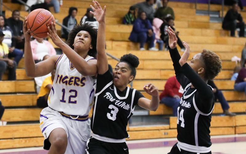 Columbia forward Jolena Gardner drives past Fort White guard Jermauni Byrd (3) and forward Isreal Hart (14) on Friday night. (BRENT KUYKENDALL/Lake City Reporter)