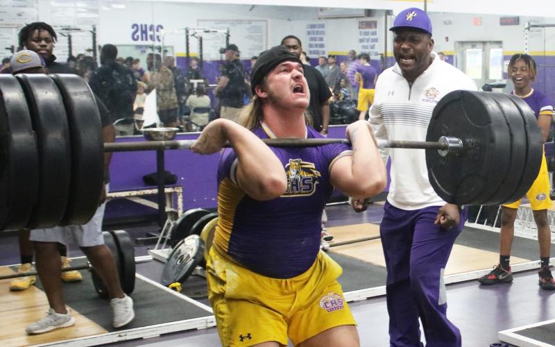 Columbia lifter Caden Bolstein raises the bar up for the clean and jerk while head coach Brian Allen yells encouragement during Wednesday’s tri-meet against Buchholz and Hamilton County. (JORDAN KROEGER/Lake City Reporter)