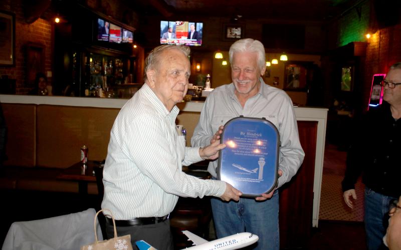 Bo Hendrick (left), who has worked at the Lake City Gateway Airport for more than 59 years, receives a gift Tuesday from Loren Triefenback from United Airlines. (TONY BRITT/Lake City Reporter)