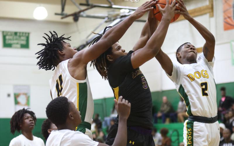 Columbia forward Jalen Gaskins (middle) fights for a rebound with Suwannee guards Jamarcus Cherry (11) and Jhy Smith (2) during Tuesday’s game. (PAUL BUCHANAN/Special to the Reporter)