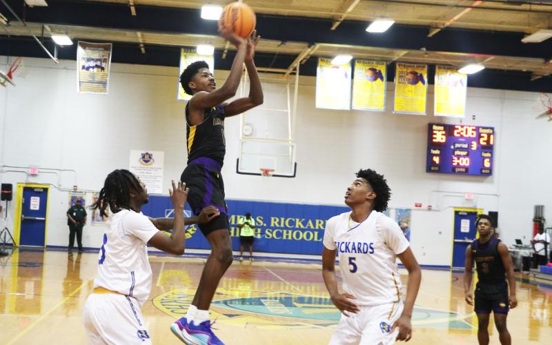 Columbia guard Noah Wilson shoots while defended by Rickards guard Chadwick Ellenwood (left) and forward Benjamin Plummer (5) during the District 2-5A championship on Saturday. (MORGAN MCMULLEN/Lake City Reporter)