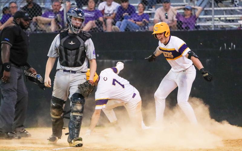 Columbia right fielder Max Schuler (right) celebrates as center fielder Bynton Edge (7) slides safely into home plate for an inside the park home run against Gainesville during Tuesday’s District 2-5A semifinal. (BRENT KUYKENDALL/Lake City Reporter)