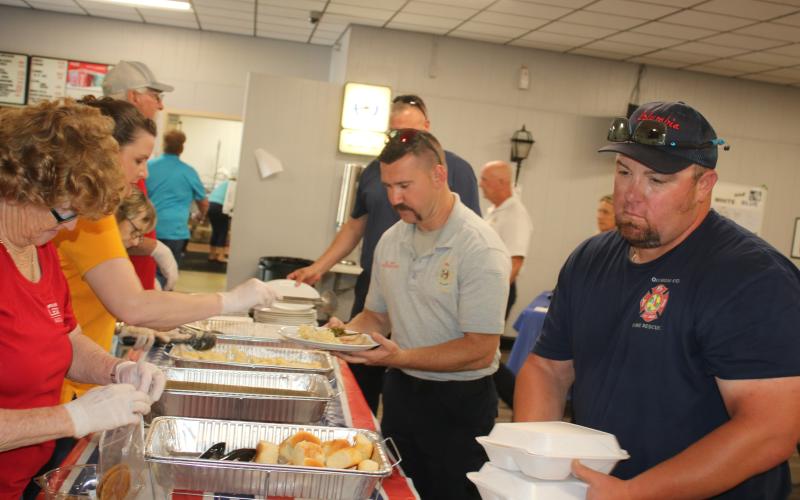 American Legion Post 57 volunteers serve meals to Columbia County Fire Rescue personnel Benjamin Fry (center) and Ronnie Crews. (TONY BRITT/Lake City Reporter)