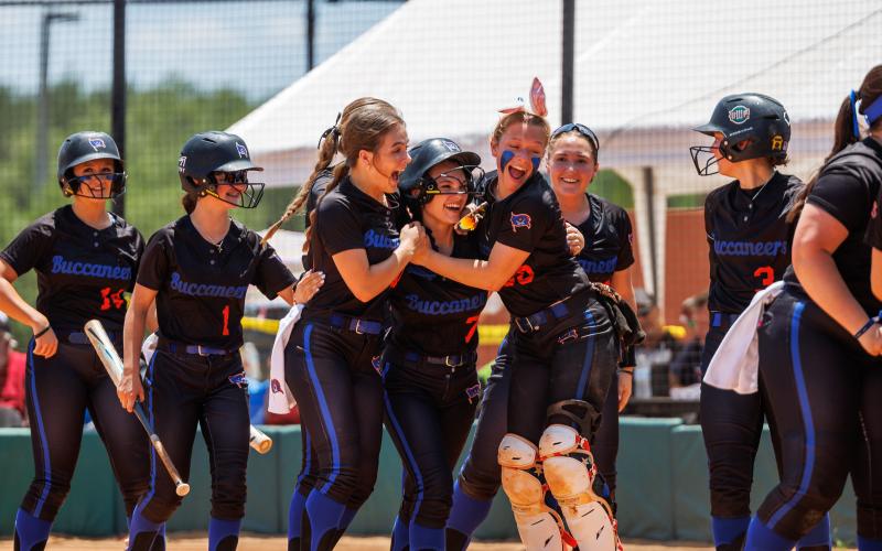 Branford outfielder Ashlee Combee (middle) is hugged by teammates Hunter Revis (left) and Morgan Brennan (right) after scoring a run against Liberty County in the Class 1A state semifinals on Friday. (JACK HOWDESHELL/Special to the Reporter)