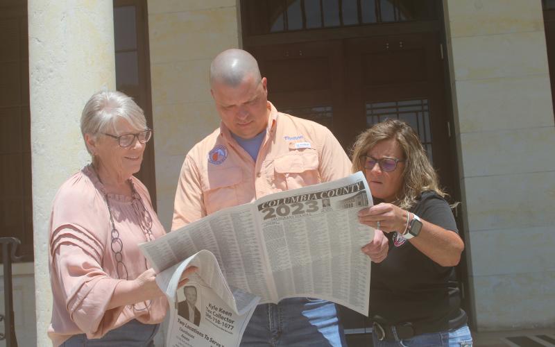 Columbia County Tax Collector’s Office employees La Gina Dow (from left), Thelton Goff and Tracy Nettles look at the county’s delinquent tax rolls Friday as the tax sales certificate auction ended. (JAMIE WACHTER/Lake City Reporter)