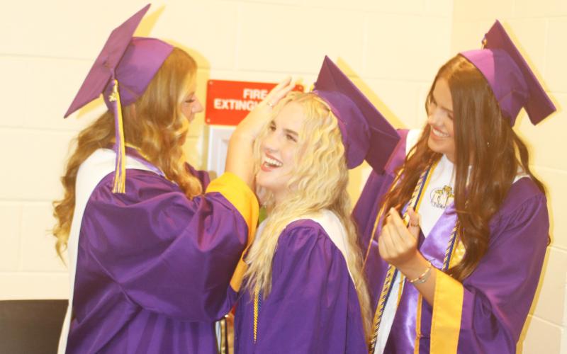 Ansley Williams (from left) adjusts Elle Grecian’s cap as Kansas Schrader also makes last minutes adjustments to Grecian’s outfit in the minutes leading up to Friday evening’s graduation at Columbia High School. (TONY BRITT/Lake City Reporter)