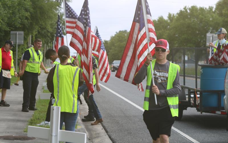 Pheonix Polansky, a cadet with the Columbia High School JROTC program, carries a flag that was later added to a cross for the Flags for Heroes display on State Road 47. (TONY BRITT/Lake City Reporter)