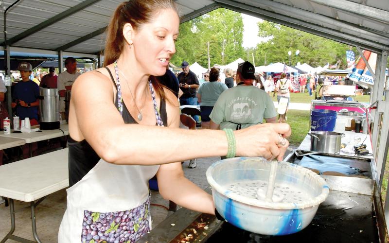 A volunteer readies to make blueberry pancakes at last year’s Wellborn Blueberry Festival. (FILE)