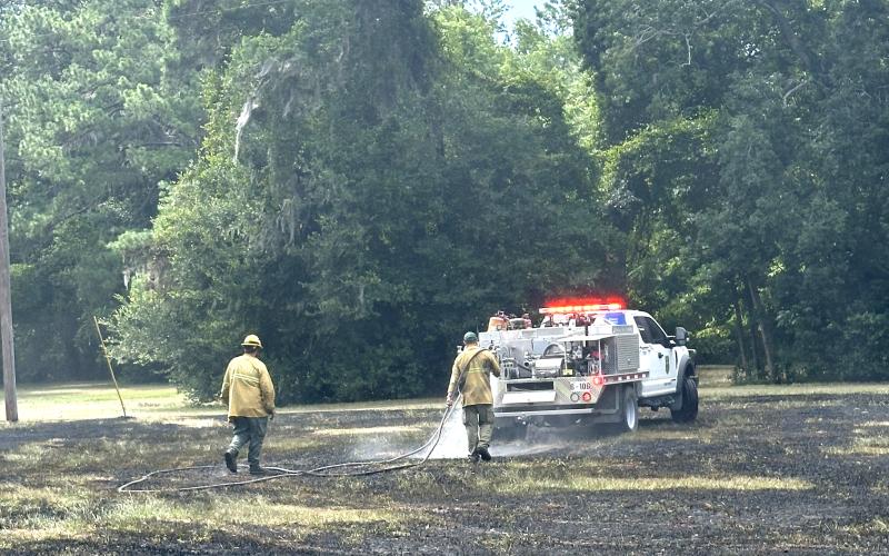 Firefighters with the Florida Forest Service help douse a grass fire at Alligator Lake Park on Wednesday afternoon. The fire was sparked by crossed power lines. (COURTESY)