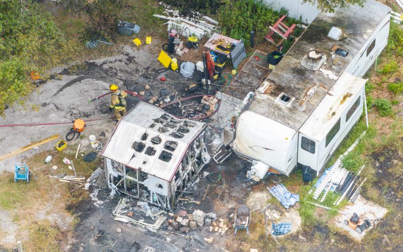 Firefighters sift through debris after a fire consumed an RV camper on State Road 47. (RAY CARPENTER/Special to the Reporter)