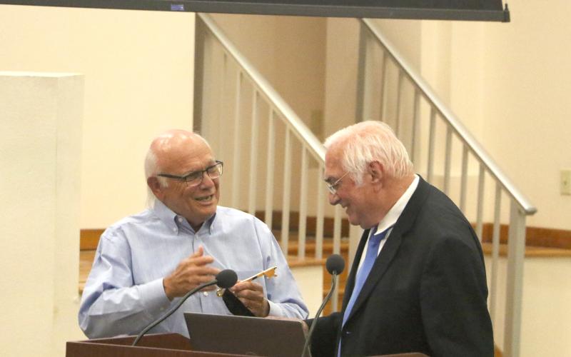 Columbia County School Board member Keith Hudson receives the key to the City of Lake City from Mayor Stephen Witt during Tuesday’s board meeting. The school board renamed the district auditorium in Hudson’s honor. Hudson has served on the board for 48 years and is running unopposed. (MORGAN MCMULLEN/Lake City Reporter)