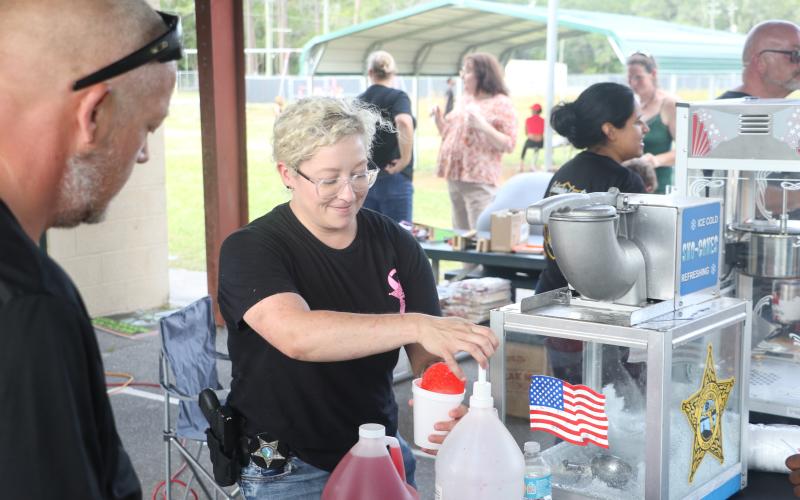 Jessica Chewning, a school resource deputy at Westside Elementary School, prepares a snow cone for a kid during Friday’s Summer Nights activities at Five Points Elementary. (MORGAN MCMULLEN/Lake City Reporter)