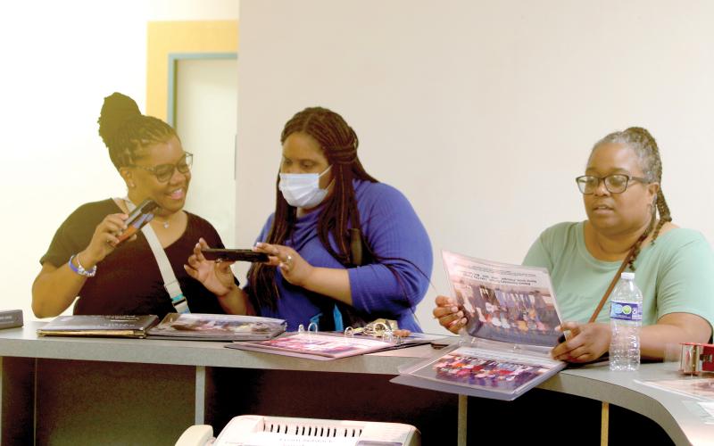 Nakitha Ivery (from left), Violet Wiggins and Nancy James look over old photos from Niblack Elementary on Sunday during a final walkthrough of the school, which is scheduled to be demolished in the near future. The school has served the community for more than 70 years. (TONY BRITT/Lake City Reporter)