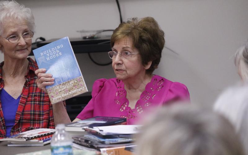 Jonnie Whittington, one of the founders of Writers Ink, holds up one of her books as she talks to the group Monday about not always getting full support in the venture from family members. Writers Ink, a group of authors, meets monthly at the Lafayette County Public Library. Delores Walker, another founder of the group, looks on. (JAMIE WACHTER/Lake City Reporter)