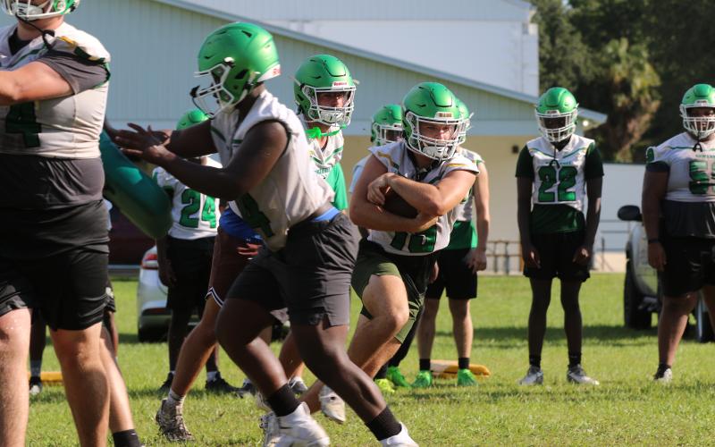 Suwannee running back Clay Starling eyes a hole after taking a handoff from quarterback Thomas Sikes during a drill in the Bulldogs' practice Monday morning. (JAMIE WACHTER/Lake City Reporter)