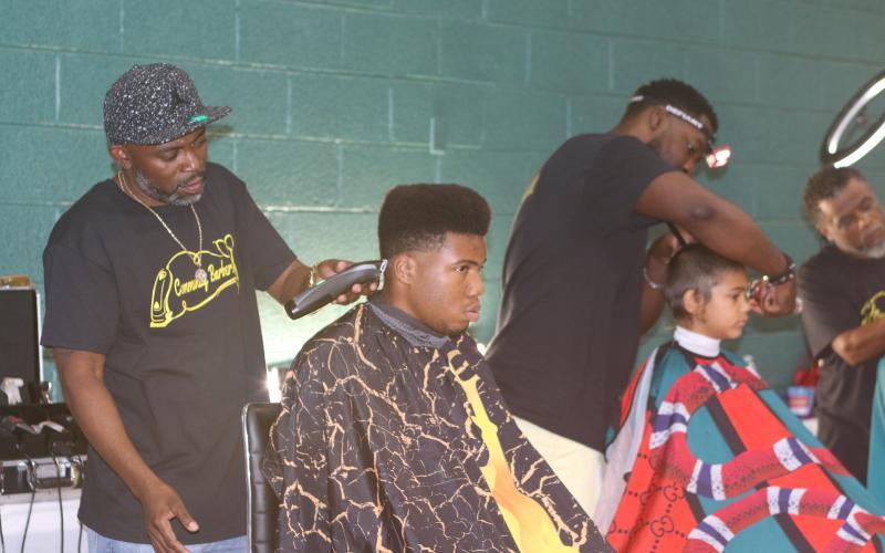 Tyrone Mullins (standing), an organizer for the Community Barbers Giving Back event, works as one of 11 barbers during the 2022 event. (FILE)