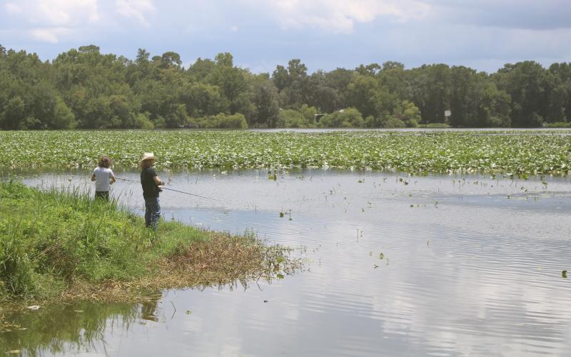 Jamie Spradley (right) and Taylor Kaus, fishing from the banks of Lake Montgomery on Monday, said a new fishing pier would be a nice addition to the lake. (TONY BRITT/Lake City Reporter)