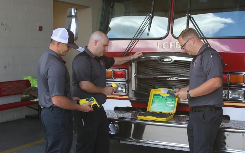 Lake City firefighters Hunter Anderson (from left), Chris Bethea and Gramby Croft look over the department’s new Electric Vehicle Plug Kit and its instruction manual. The newly purchased tool went into service for the department on Monday. (TONY BRITT/Lake City Reporter)