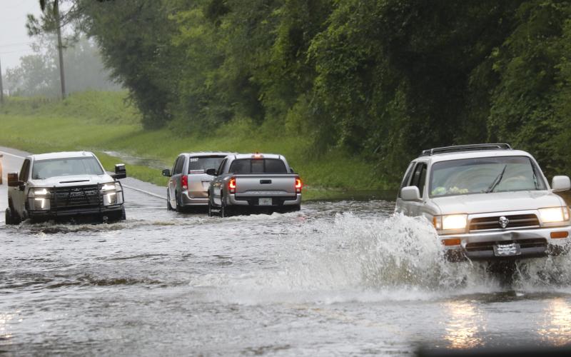 Vehicles drive through flood waters on Branford Highway (State Road 247) on Monday afternoon after Hurricane Debby drenched the area with approximately 10 inches of rain. (STASI WACHTER/Special to the Reporter)