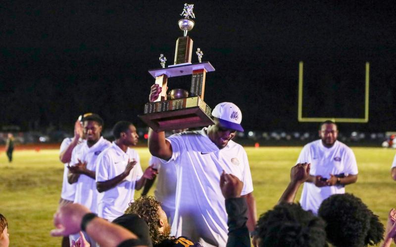 Columbia coach Brian Allen raises the Old Oaken Bucket trophy after his team defeated Suwannee 13-0 on Friday. (BRENT KUYKENDALL/Lake City Reporter)