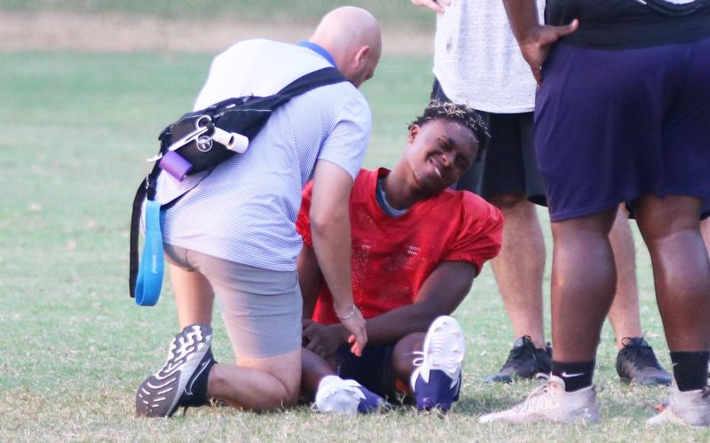 Columbia quarterback Xavier Collins has his knee attended to by the team trainer after being injured at the end of Monday’s practice. (JORDAN KROEGER/Lake City Reporter)