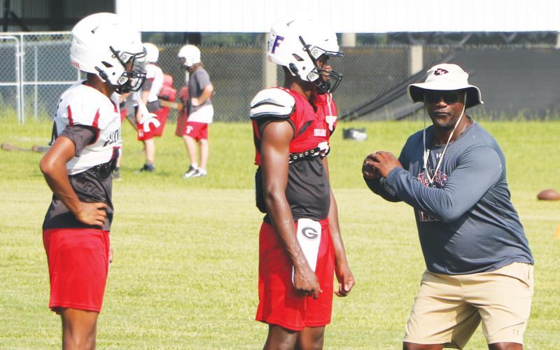 Fort White coach Demetric Jackson (right) works with quarterbacks Gavin Peterson (left) and Jayden Jackson (middle) during practice on Aug. 8. (MORGAN MCMULLEN/Lake City Reporter)