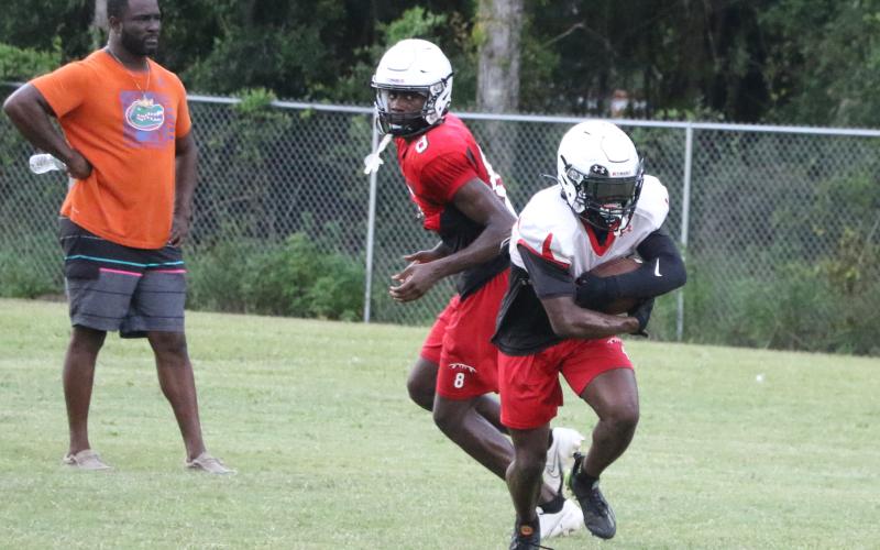 Fort White running back Keimarion Neal takes a handoff from quarterback Jayden Jackson during Thursday's practice. (MORGAN MCMULLEN/Lake City Reporter)