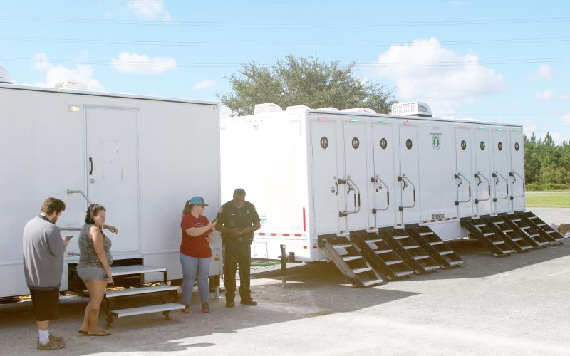 Keith Brown (from left), Sherri Woods and Kate Reeves talk to CCSO Deputy Greg Williams on Sunday while utilizing laundry units in Southside Sports Complex. (TONY BRITT/Lake City Reporter)