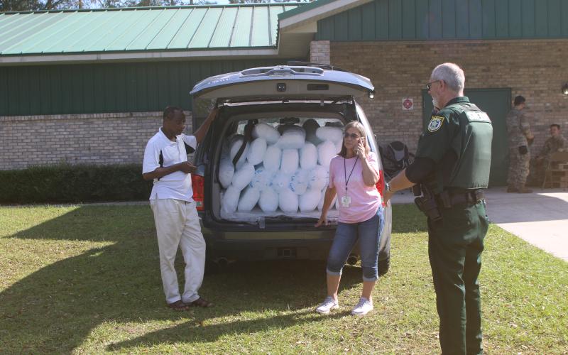 Susan Kroh (middle) and Columbia County Sheriff's Deputy Brian Rix (right) attempt to figure out what to do with 1,000 pounds of ice delivered to the Deep Creek Community Center on Sunday afternoon in the back of a Honda Pilot. (TONY BRITT/Lake City Reporter)