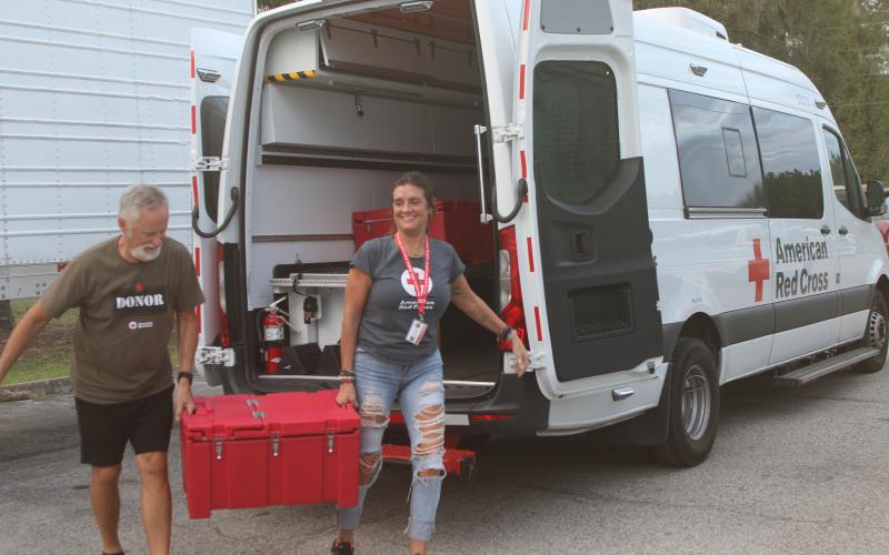 Red Cross workers unload hot meals out of an American Red Cross Emergency Response Vehicle on Monday evening at the Fort White Community Center. Red Cross served Shepherd's Pie and bread prepared by Big D's Barbecue in Tallahassee as dinner to people without power from Hurricane Helene. (TONY BRITT/Lake City Reporter)