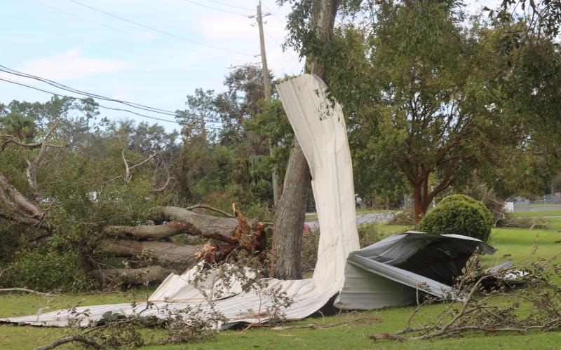 Tin from the roof of First Advent Christian Church lays on the ground with a fallen tree in front of Suwannee Springcrest Elementary School on Saturday. (LILLY WACHTER/Lake City Reporter)