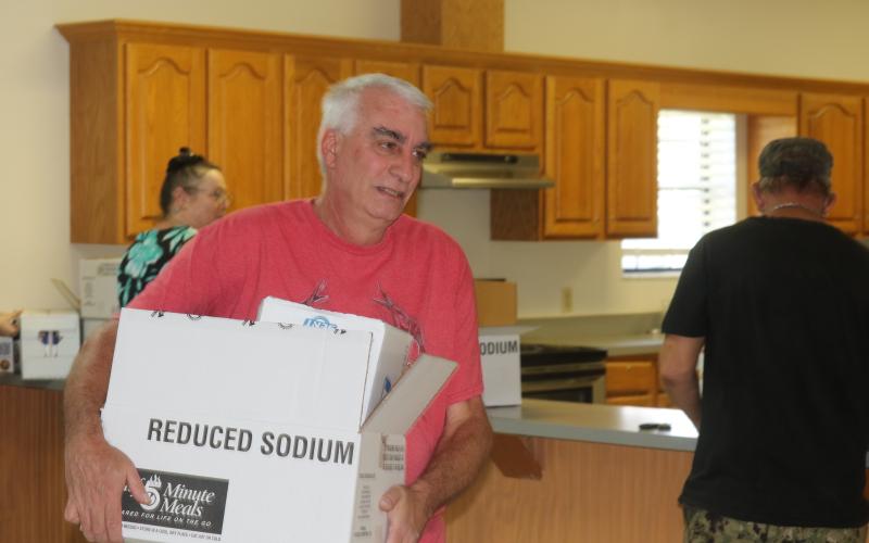 Carl Lynn carries his MREs and water out of the Fort White Community Center on Sunday afternoon. Lynn's biggest concern moving forward without power is for the welfare of his animals on his 30 acres in southern Columbia County. (STASI WACHTER/Lake City Reporter)