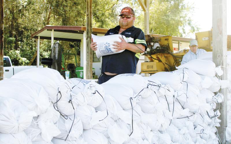 Columbia County Public Works employee Steve ‘Bacon’ Allen carries a sandbag to a pile of bags Tuesday afternoon as the county prepared for the impacts of Tropical Storm Helene, which is expected to make landfall Thursday. (TONY BRITT/Lake City Reporter)