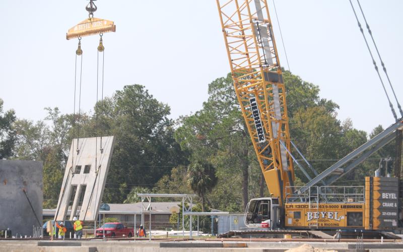 Construction workers help lower a section of one of the walls of the new Niblack Elementary School into position Monday. The walls are being put into place over the next two weeks. (TONY BRITT/Lake City Reporter)