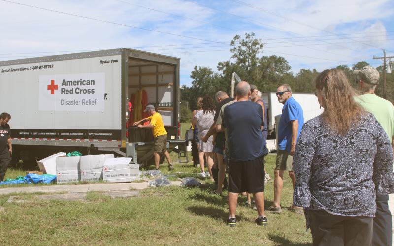 Southern Columbia County residents stand in line to get supplies, including shovels, rakes, tarps, buckets and cleaning supplies, from the American Red Cross in Fort White on Thursday. (TONY BRITT/Lake City Reporter)