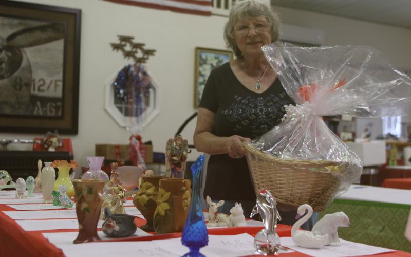 Vicki Shanks, who is helping organize the Gateway Art Gallery silent auction, shows off items that will be available during the fundraiser later in the month. (TONY BRITT/Lake City Reporter)