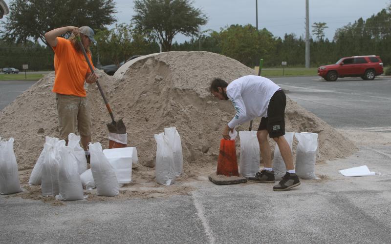 Jasper Webb (from left) and Jonathan Hughes fill sandbags as they prepare for Hurricane Milton. (TONY BRITT/Lake City Reporter)