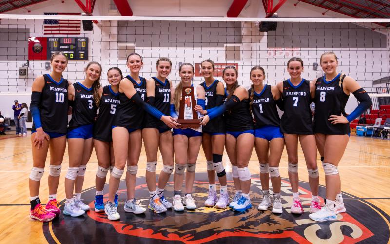 Branford's volleyball team poses with the District 6-R trophy after sweeping Union County on Thursday night. (JACK HOWDESHELL/Lake City Reporter)