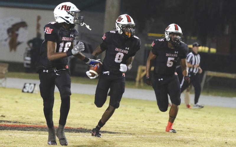 Fort White’s Jayden Jackson (8) looks for room to run on his first interception return for a touchdown Friday against Hilliard as DeSean Lally (16) and Darion Brinson (5) look to make a block. (MORGAN MCMULLEN/Lake City Reporter)