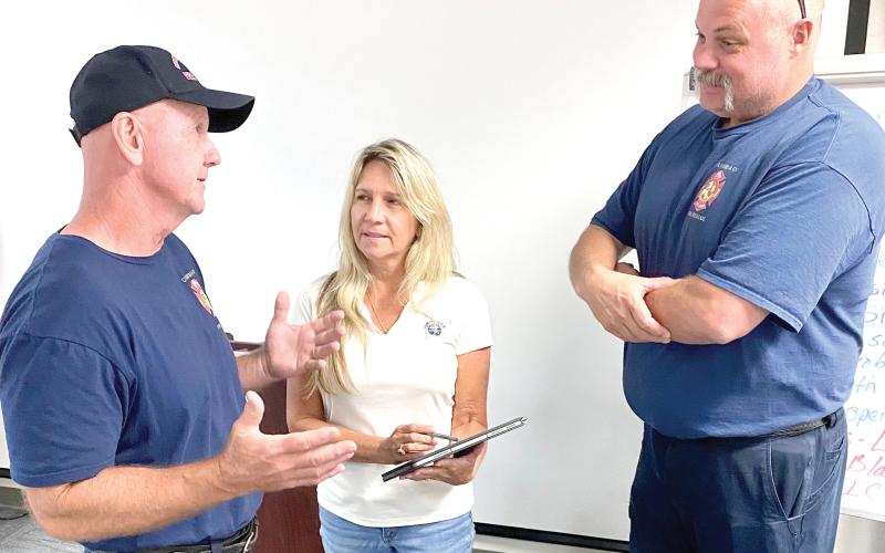 Columbia County Fire Chief Jeff Crawford (from left), Columbia County Sheriff’s Office employee Hope Crawford and Assistant Fire Chief Lance Hill discuss the rescue of Ken Stapleton, 66, of Fort White, who was pinned in his truck after a tree fell on it during the height of Hurricane Helene early Friday morning. (TODD WILSON/Lake City Reporter)
