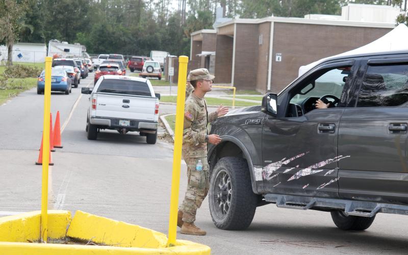 A member of the Florida National Guard helps direct vehicles at a POD (Points of Distribution) site at RIVEROAK Technical College in Live Oak on Saturday. That location has now been moved to the Live Oak Mall at 841 Pinewood Drive SW. (JAMIE WACHTER/Lake City Reporter)