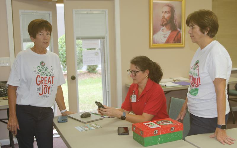 Beth Bullard (from left), Cheri Schultz and Lou Blanton, volunteers at the Operation Christmas Child Shoebox Collection Center in Lake City, work with other volunteers to collect and ship the shoeboxes to Atlanta. (TONY BRITT/Lake City Reporter)