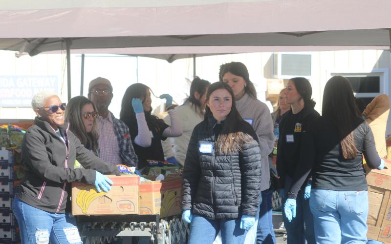 Xavier White (left) and Taylor Carroll wait for a client from Catholic Charities to park their vehicle so they can unload boxes of food into the car. Catholic Charities served approximately 650 people during this year’s Thanksgiving food distribution. (TONY BRITT/Lake City Reporter)