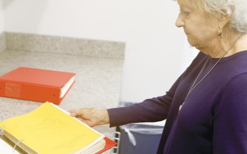 Mary Loughran, the daughter of Mary Ethel Anderson, looks through a binder containing some of the ‘Goodie Books’ that her mother created as a county extension service agent. (TONY BRITT/Lake City Reporter)