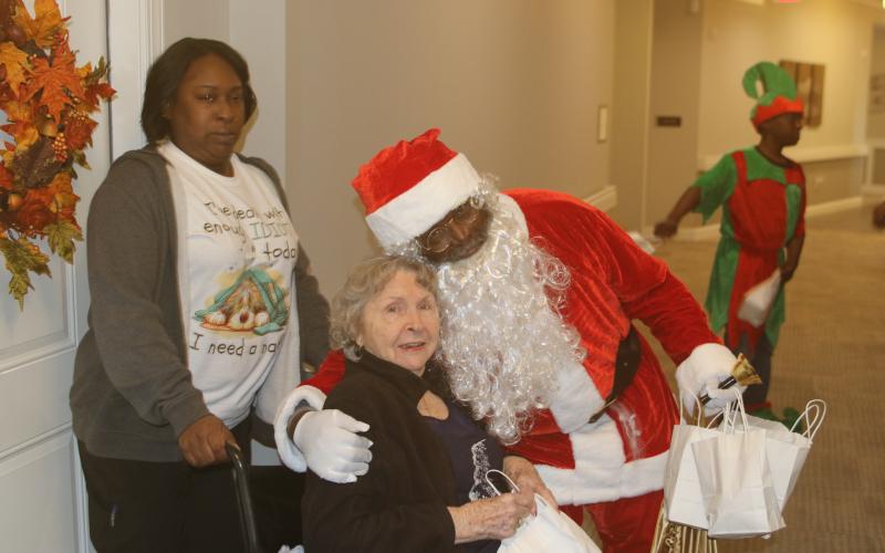 Trudie Johns gets a hug from Joseph Simmons, who portrayed Santa Claus on Sunday afternoon when members of the Our Community Cares Coalition visited residents at The Canopy at Harper Lake. (TONY BRITT/Lake City Reporter)