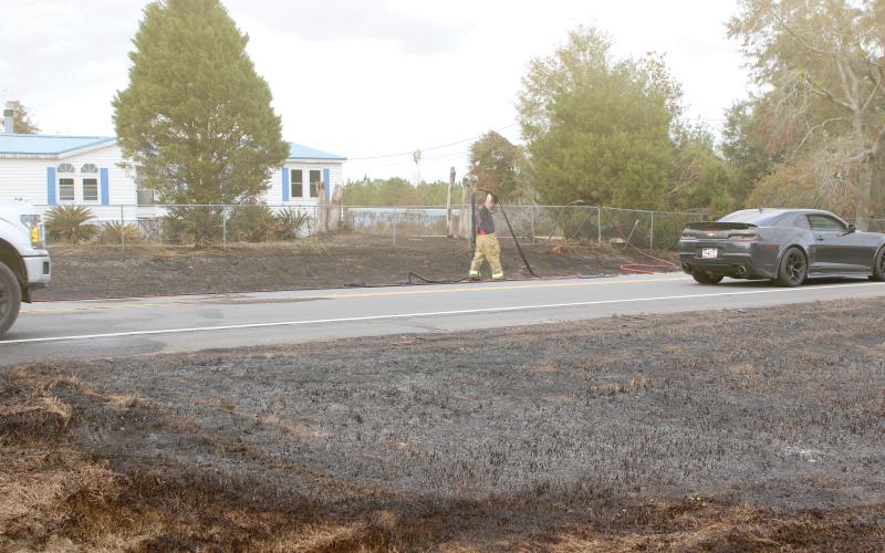 A Columbia County firefighter extends a hose as firefighters and law enforcement officers battled a brush fire Saturday afternoon on State Road 47 that jumped the road and threatened a home. (TONY BRITT/Lake City Reporter)